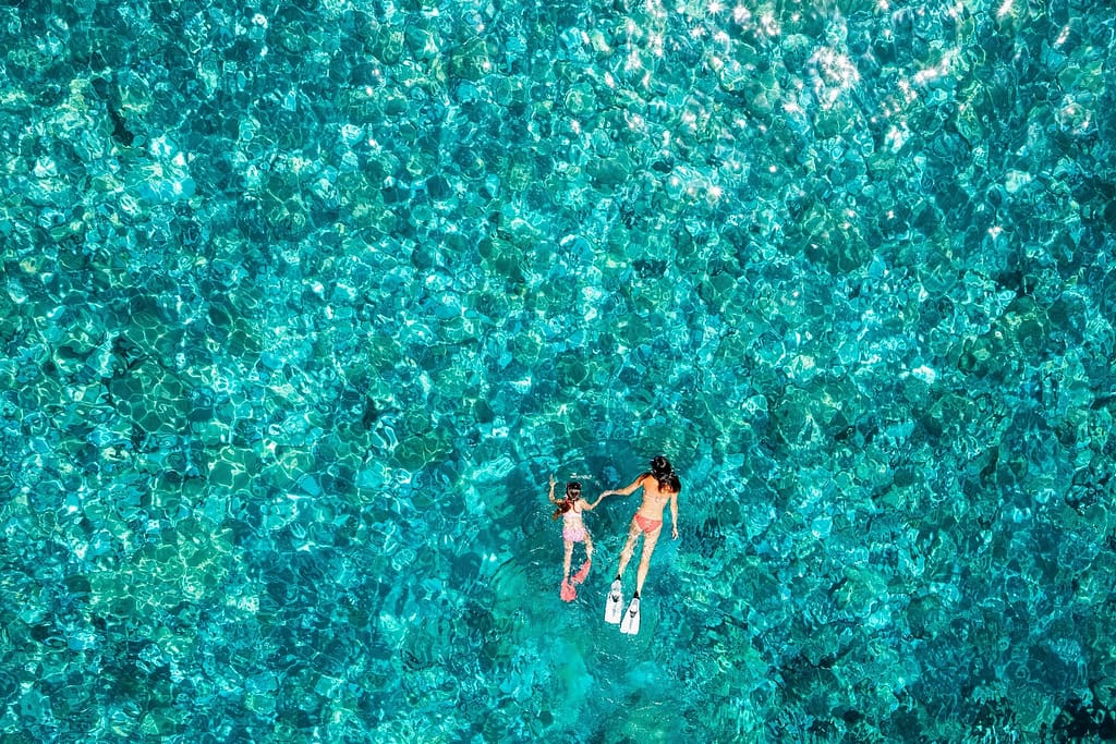 Mutter und Tochter schwimmen im Meer bei Sonnenschein