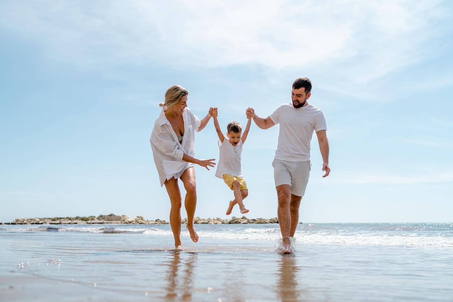 Glückliche Familie mit Kind läuft am Strand. Leben und Auswandern nach Zypern