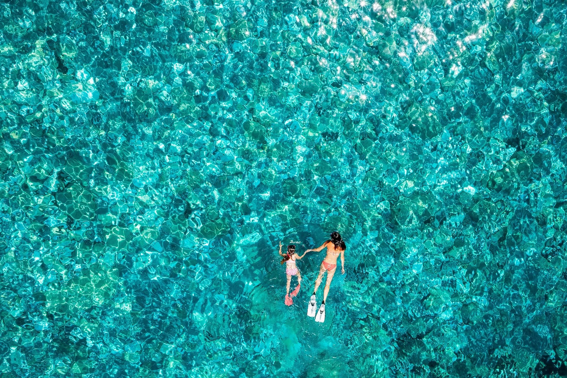 Mutter und Tochter schwimmen im Meer bei Sonnenschein